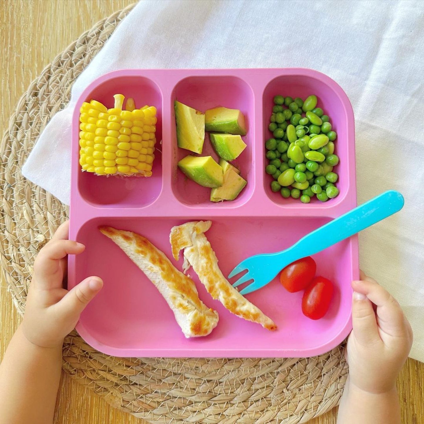 Bobo&boo pink plant-based divided plate for toddlers with chicken & vegetables & a blue fork