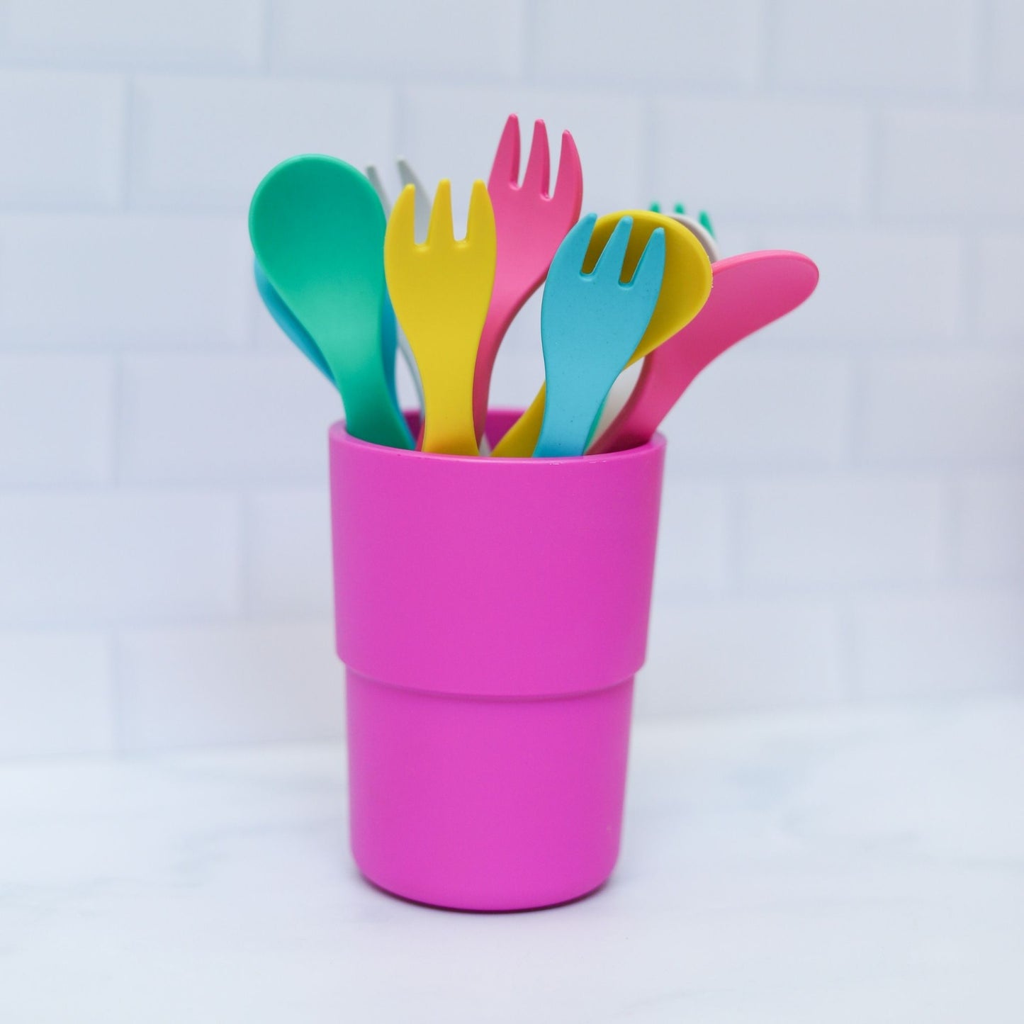 bamboo plant-based cutlery in mixed vibrant colours sitting in a pink cup