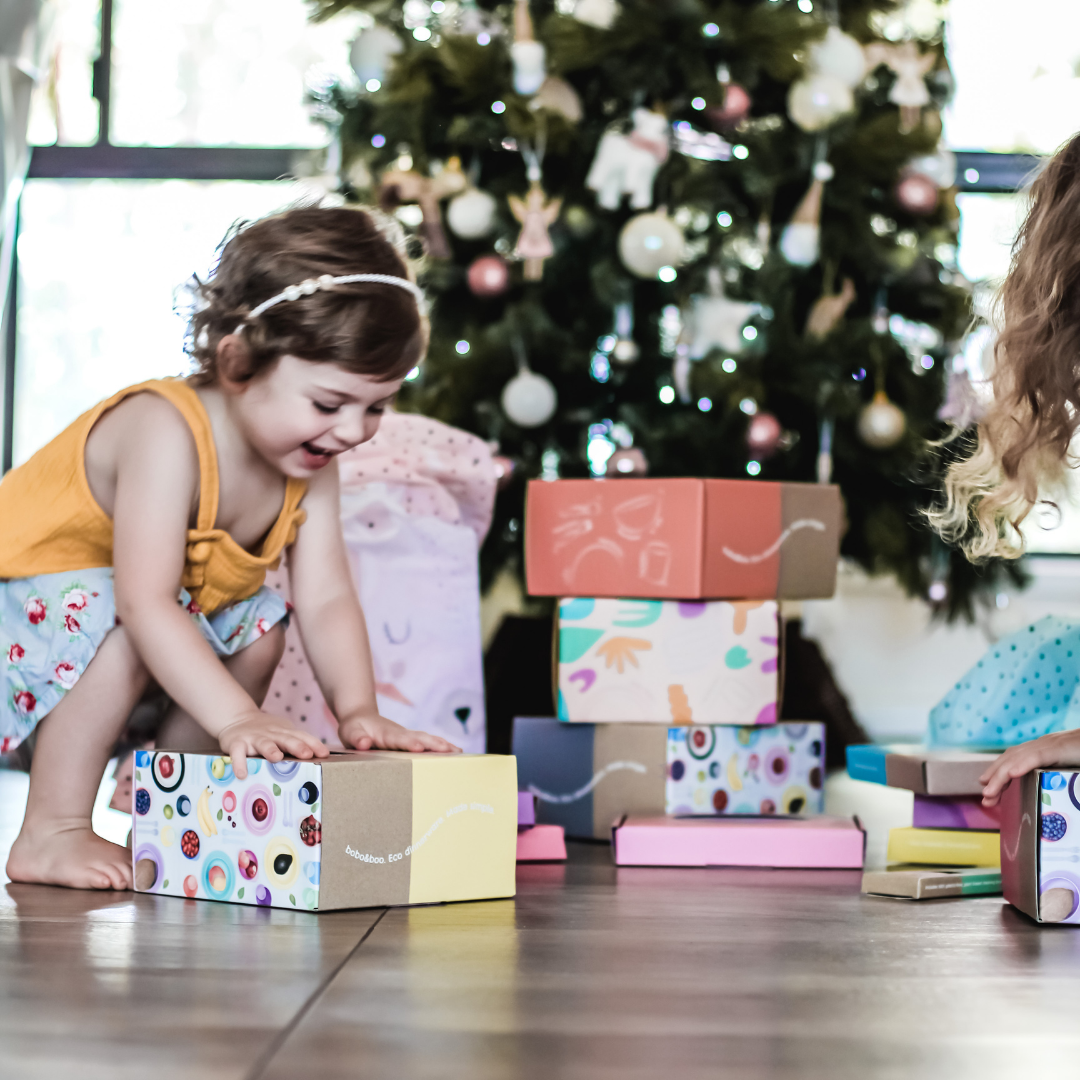 girl with bobo&boo gift boxes in front of a Christmas tree