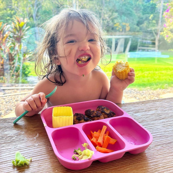happy child eating her veggies off her bento plate