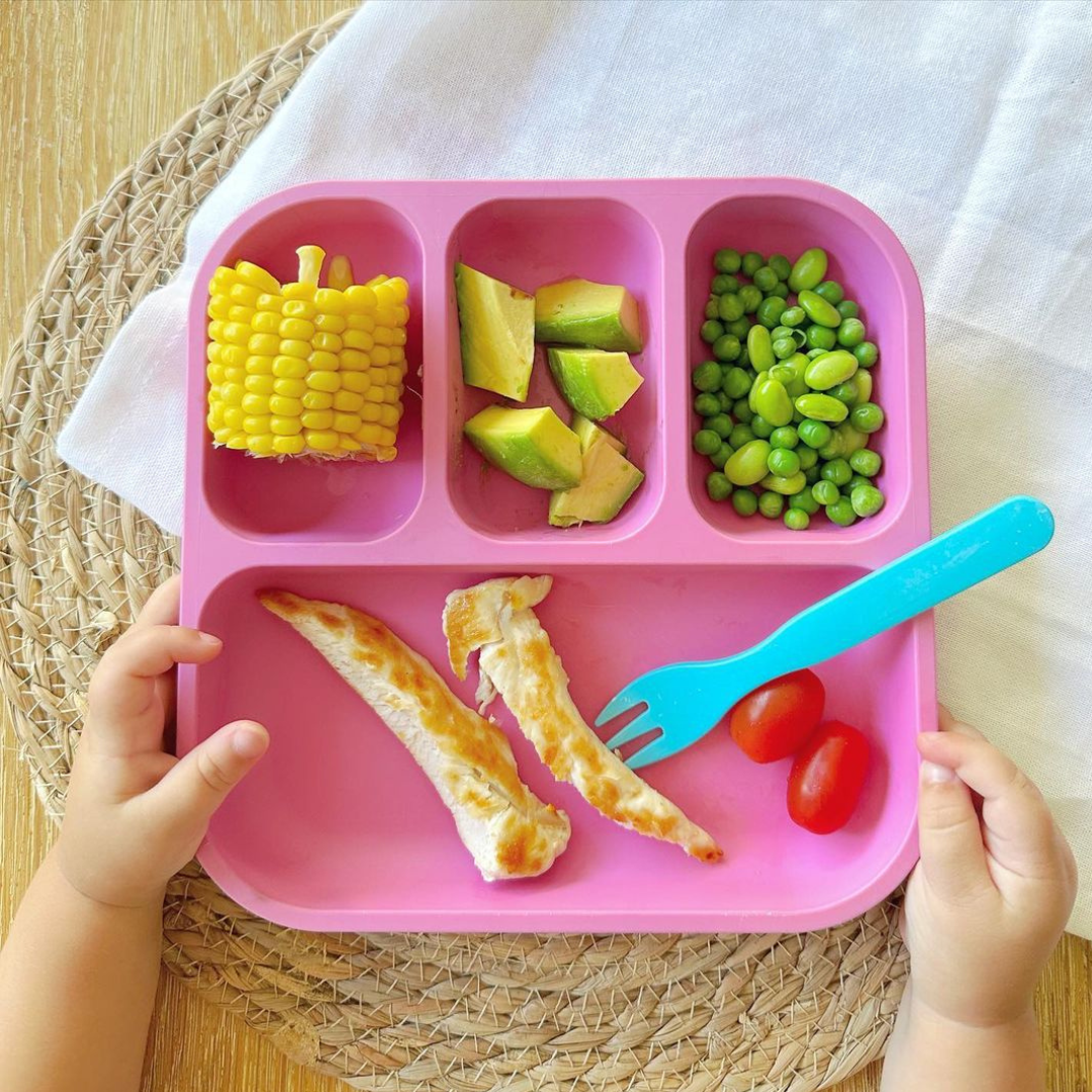 kids hands holding a bento plate with vegetables in the compartments