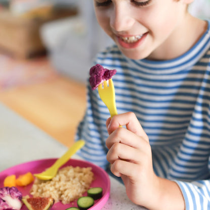 a boy using a bobo&boo plant-based oak while eating purple broccoli 
