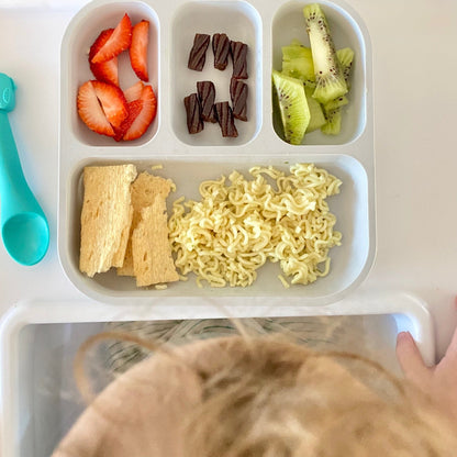 toddler sitting in a high chair eating out of a bobo&boo plant-based bento plates with snacks